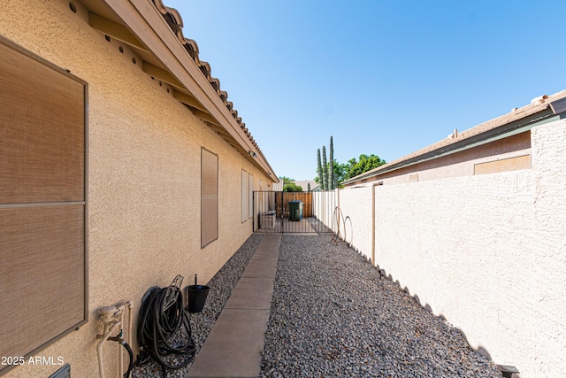 view of side of home with a fenced backyard and stucco siding