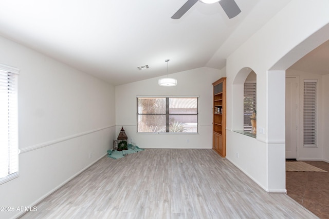 empty room featuring ceiling fan, visible vents, wood finished floors, lofted ceiling, and baseboards