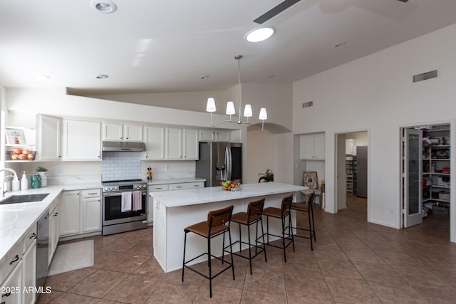 kitchen with high vaulted ceiling, visible vents, appliances with stainless steel finishes, under cabinet range hood, and a sink