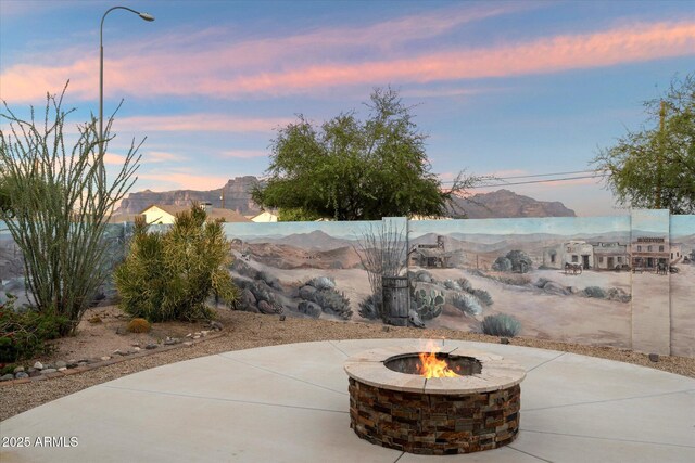2487 S Conestoga Rd, Apache Junction, AZ 85119 - patio terrace at dusk featuring a fire pit, a patio area, and a mountain view