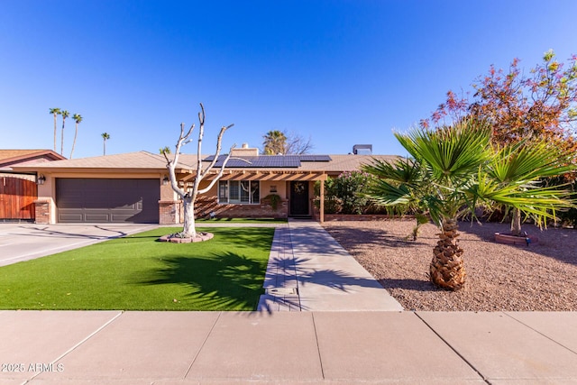 ranch-style house featuring a garage, a front lawn, and solar panels