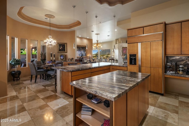 kitchen featuring an inviting chandelier, hanging light fixtures, a tray ceiling, and kitchen peninsula