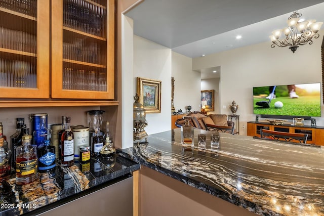 bar with an inviting chandelier, decorative light fixtures, and dark stone countertops