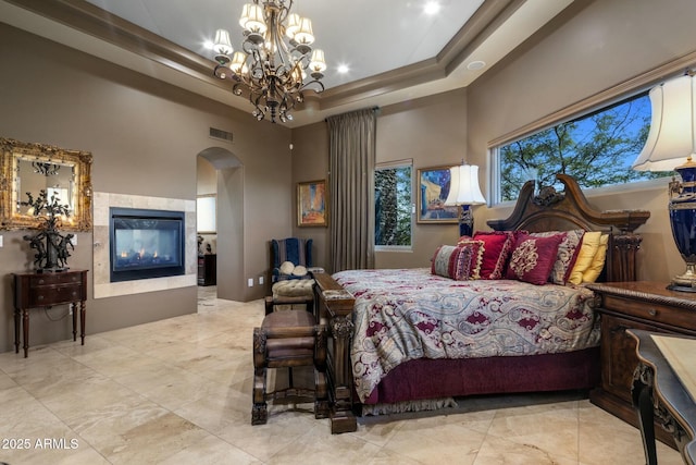 bedroom featuring a notable chandelier, a tray ceiling, a towering ceiling, and a multi sided fireplace