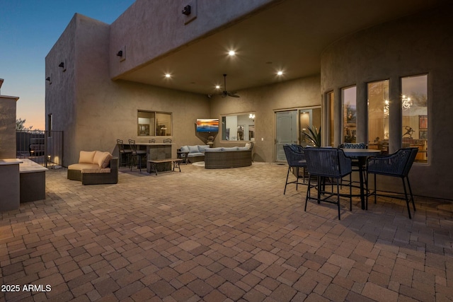 patio terrace at dusk with an outdoor living space and ceiling fan