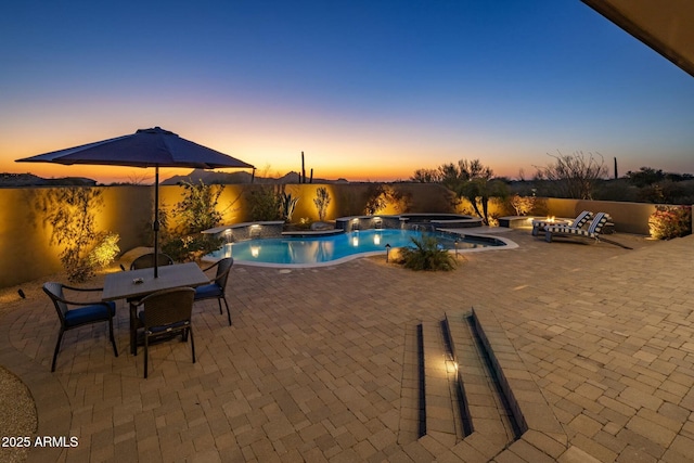 pool at dusk with an in ground hot tub and a patio