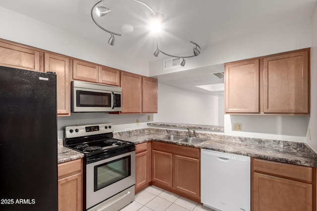 kitchen with appliances with stainless steel finishes, light tile patterned flooring, a sink, and visible vents