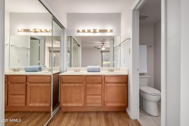 full bathroom featuring double vanity, wood finished floors, a sink, and a ceiling fan