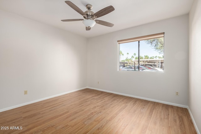 empty room with ceiling fan, light wood-style flooring, and baseboards