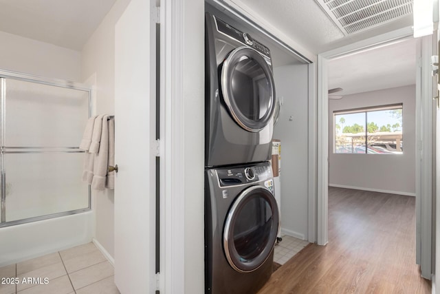 laundry room featuring laundry area, stacked washer and clothes dryer, visible vents, and baseboards