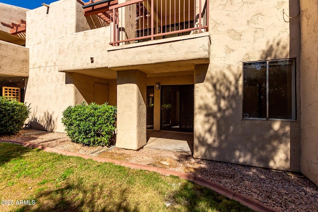 entrance to property featuring a balcony and stucco siding