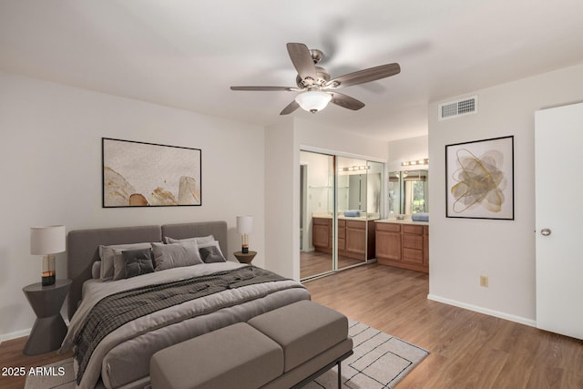 bedroom with light wood finished floors, baseboards, visible vents, and ensuite bathroom