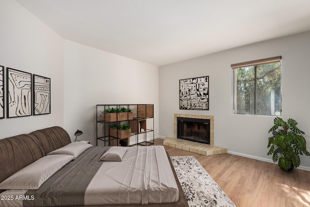 bedroom with a fireplace, wood finished floors, and baseboards