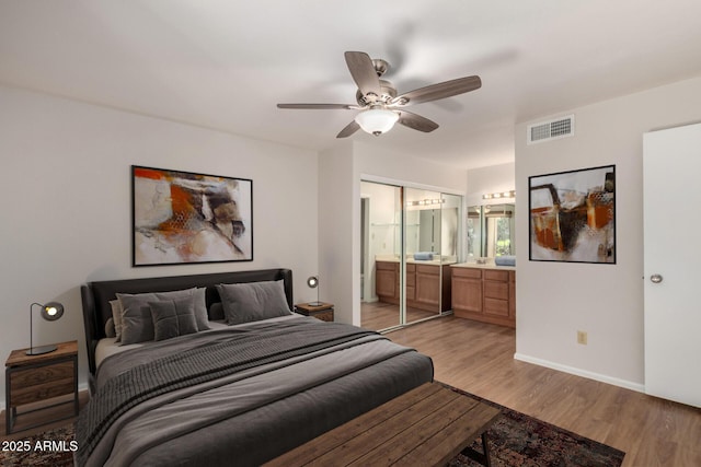 bedroom with visible vents, baseboards, a ceiling fan, ensuite bath, and light wood-style floors