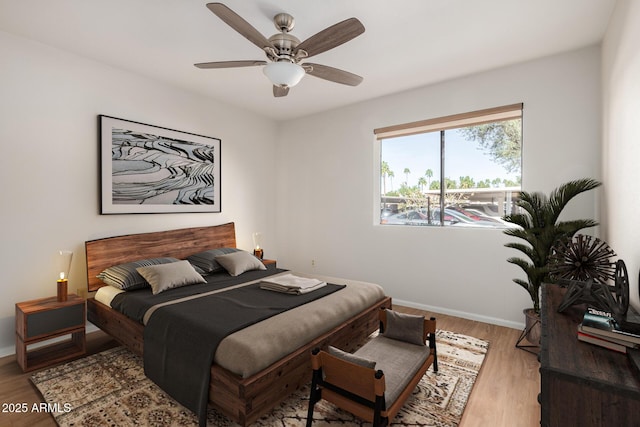 bedroom with a ceiling fan, baseboards, and wood finished floors