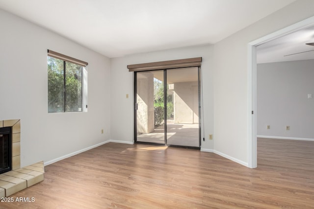 unfurnished living room with light wood-type flooring, a healthy amount of sunlight, a fireplace, and baseboards