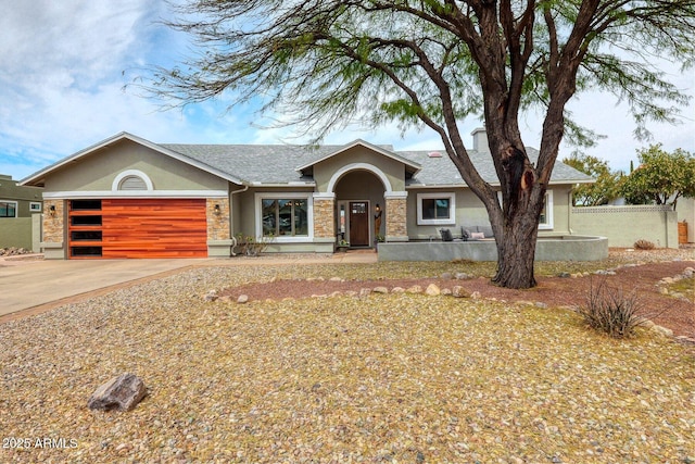 ranch-style house with stucco siding, concrete driveway, an attached garage, fence, and stone siding