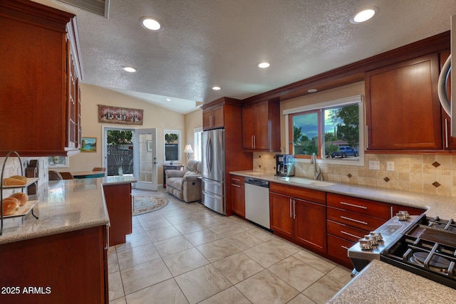 kitchen with stainless steel appliances, lofted ceiling, a sink, and tasteful backsplash