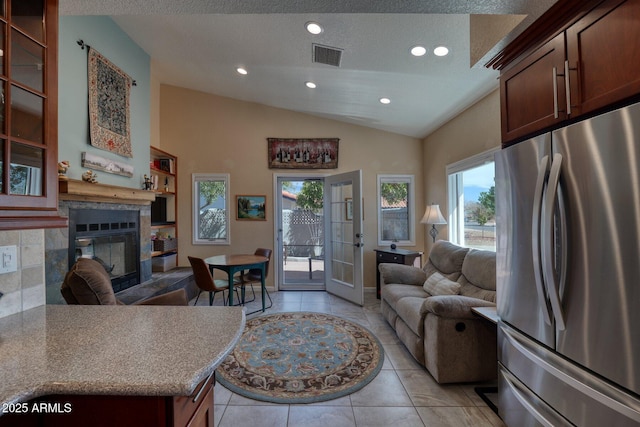 living area featuring visible vents, a glass covered fireplace, lofted ceiling, french doors, and recessed lighting