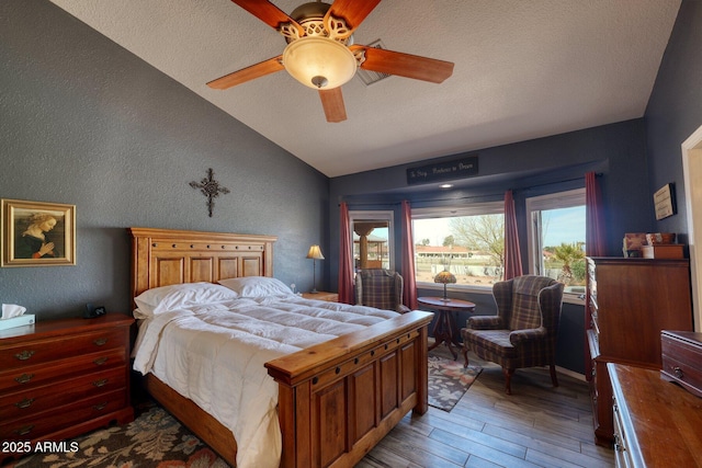 bedroom with lofted ceiling, a textured wall, light wood-style floors, a ceiling fan, and a textured ceiling