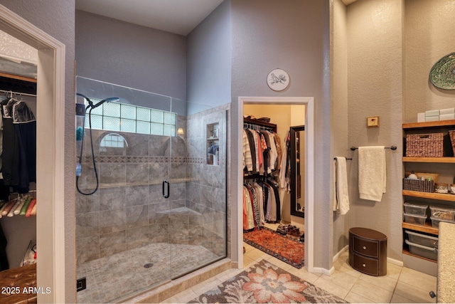 full bathroom with a stall shower, a spacious closet, and tile patterned floors