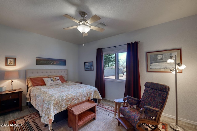 bedroom with visible vents, a ceiling fan, a textured ceiling, wood finished floors, and baseboards