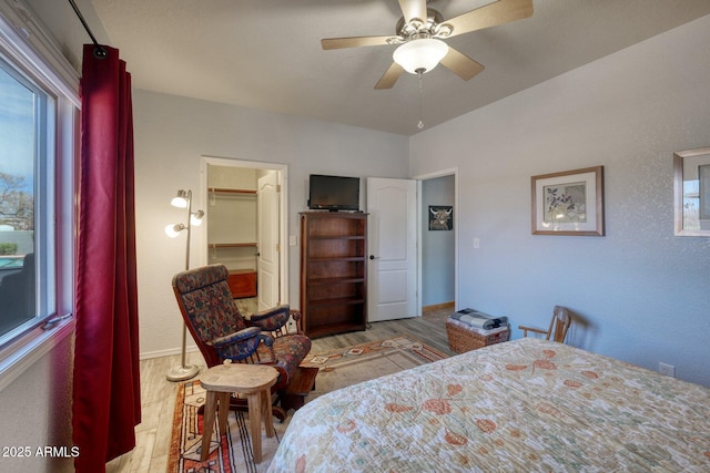 bedroom with ceiling fan, multiple windows, wood finished floors, and baseboards