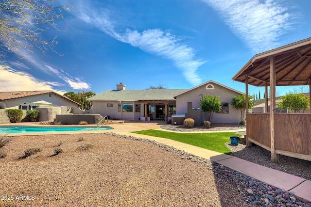 back of house featuring fence, a fenced in pool, stucco siding, a chimney, and a patio area