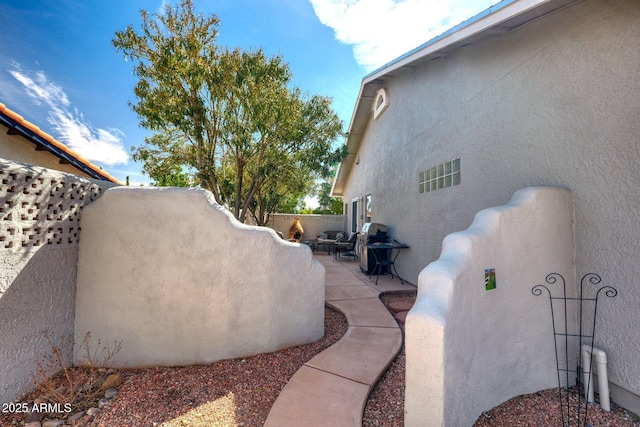 exterior space featuring a patio area, fence, and stucco siding