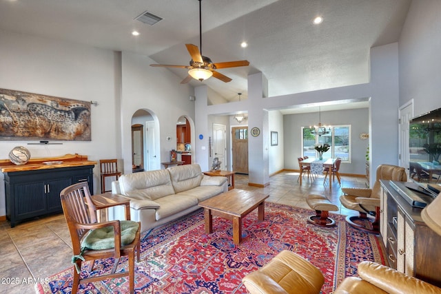 living room featuring arched walkways, light tile patterned floors, visible vents, high vaulted ceiling, and ceiling fan with notable chandelier