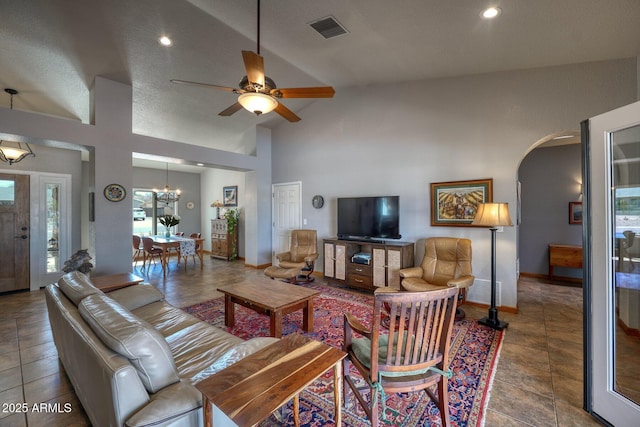 living area featuring arched walkways, high vaulted ceiling, visible vents, baseboards, and tile patterned floors