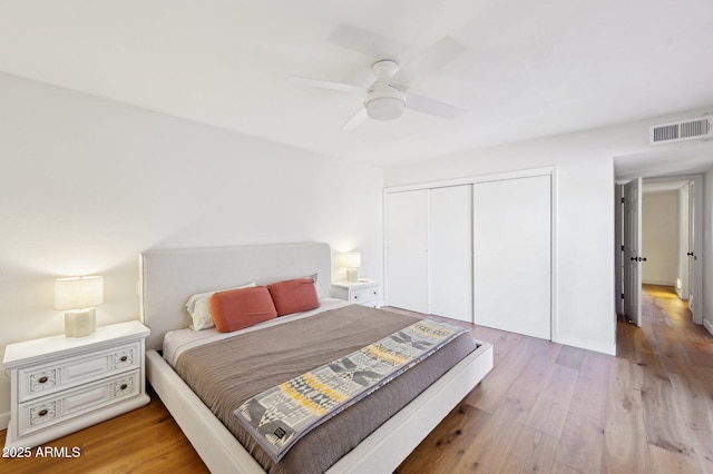 bedroom with light wood finished floors, a ceiling fan, visible vents, and a closet