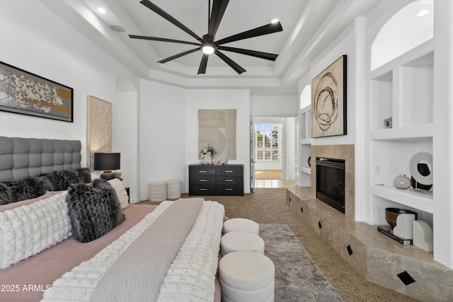 bedroom featuring a high ceiling, ceiling fan, and a fireplace