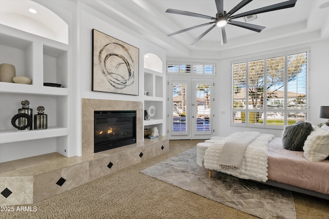 bedroom featuring a tray ceiling, carpet floors, ceiling fan, a high end fireplace, and access to exterior