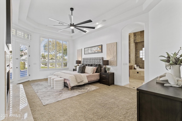 bedroom featuring ceiling fan, access to exterior, connected bathroom, a tray ceiling, and light carpet