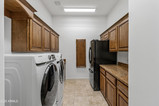 laundry area featuring cabinets, light tile patterned floors, and washing machine and clothes dryer