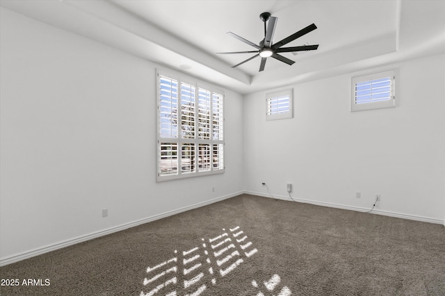 carpeted spare room with ceiling fan and a raised ceiling