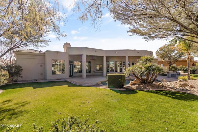 rear view of house with a yard, ceiling fan, and a patio area