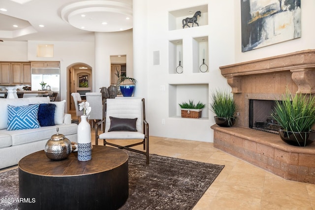 living area with tile patterned floors, a high ceiling, a tiled fireplace, and recessed lighting