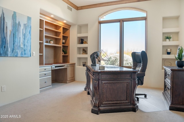 office area with built in shelves, visible vents, crown molding, and light carpet