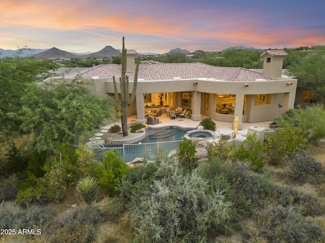 back of property with a patio, stucco siding, a mountain view, a fenced backyard, and an outdoor living space