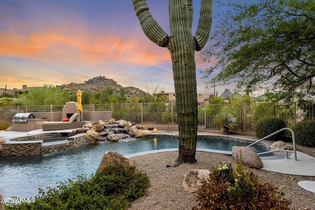 view of pool with area for grilling, fence, and a pool with connected hot tub