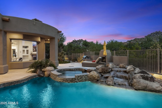 pool at dusk featuring an in ground hot tub, a patio, fence, and a fenced in pool