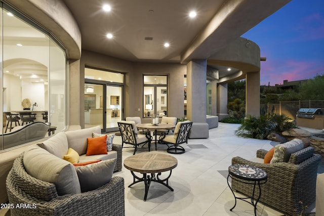 patio terrace at dusk featuring outdoor lounge area, fence, and visible vents