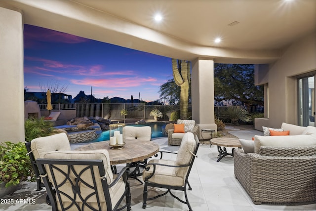 patio terrace at dusk featuring a fenced in pool, outdoor dining area, a fenced backyard, and an outdoor hangout area