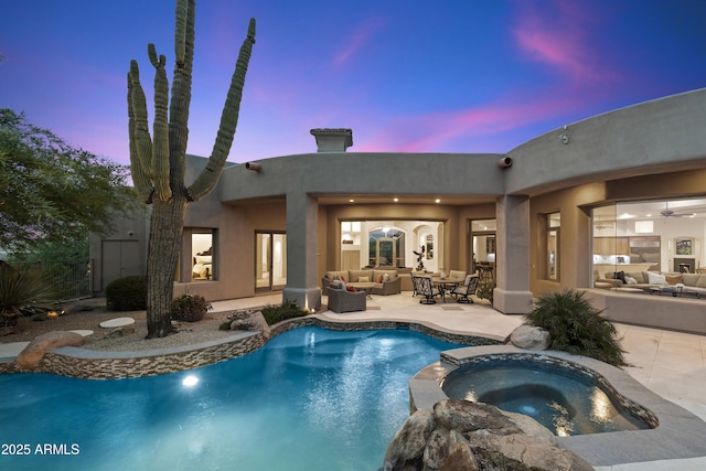 pool at dusk with a pool with connected hot tub, an outdoor hangout area, and a patio