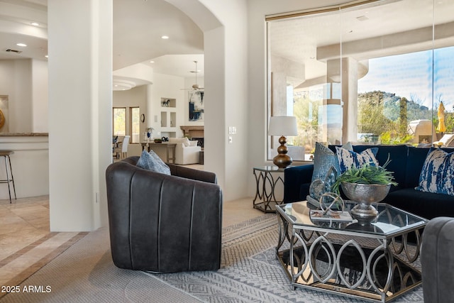 living area featuring arched walkways, a fireplace, visible vents, and recessed lighting