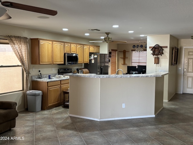 kitchen with a healthy amount of sunlight, ceiling fan, stainless steel appliances, and an island with sink