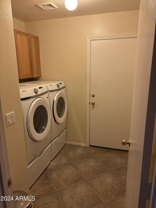 clothes washing area featuring cabinets, dark tile patterned floors, and independent washer and dryer