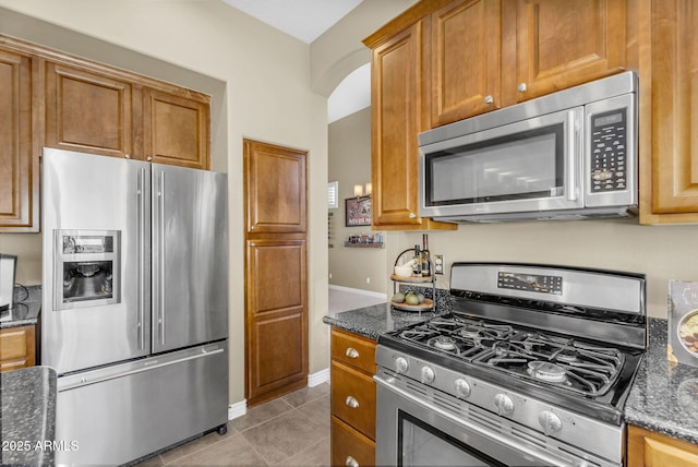 3859 N El Sereno St, Mesa, AZ 85207 - kitchen with appliances with stainless steel finishes, dark stone countertops, light tile patterned flooring, and brown cabinets